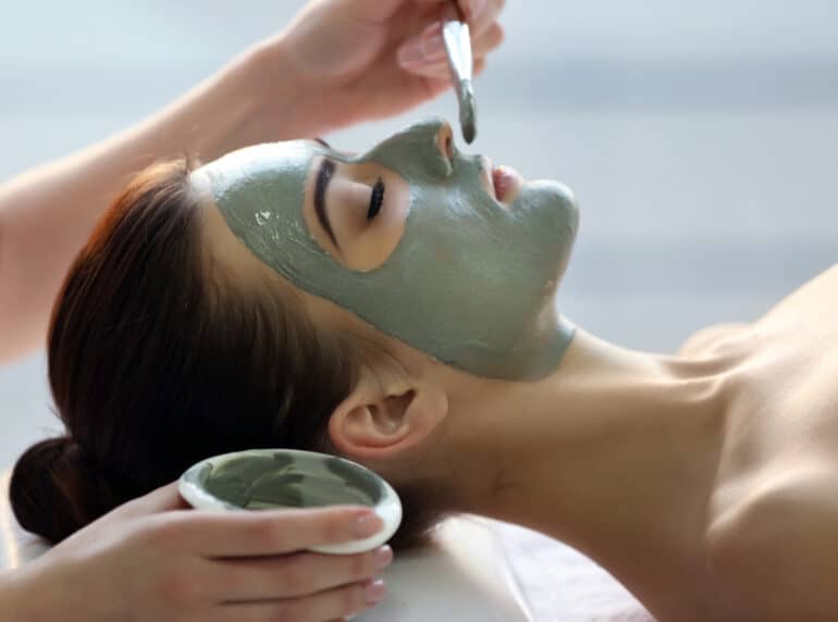 green face mask being applied to a woman's face