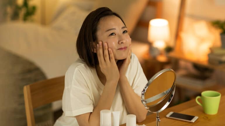 Young Asian woman doing her facial beauty routine in bedroom