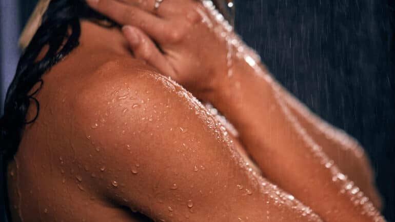 Closeup of a woman's shoulder, tanned and covered in water droplets