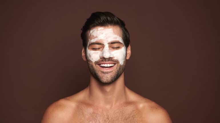 smiling young man with beauty mask on his face