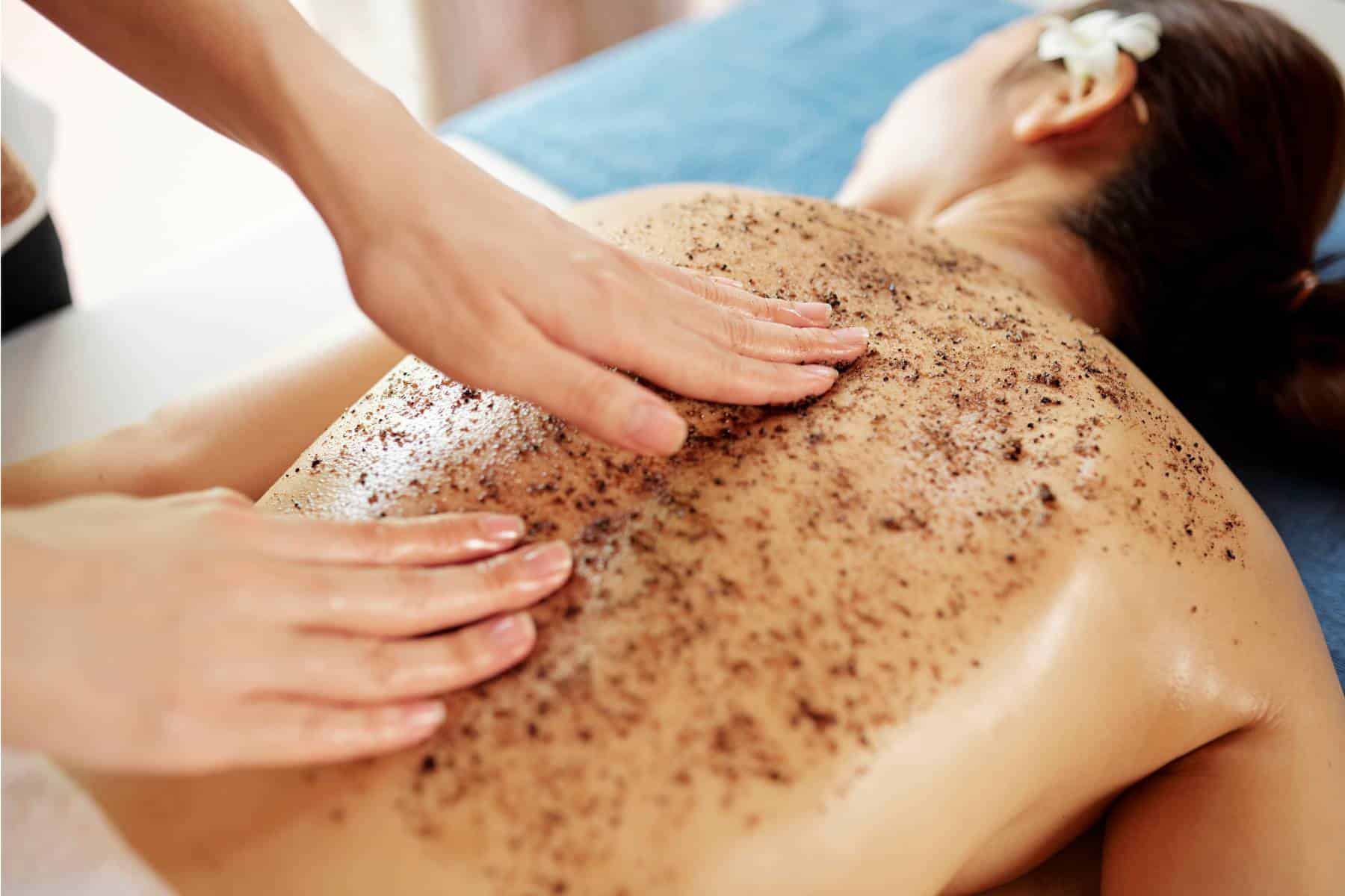 woman receiving a body scrub treatment on her back at a spa