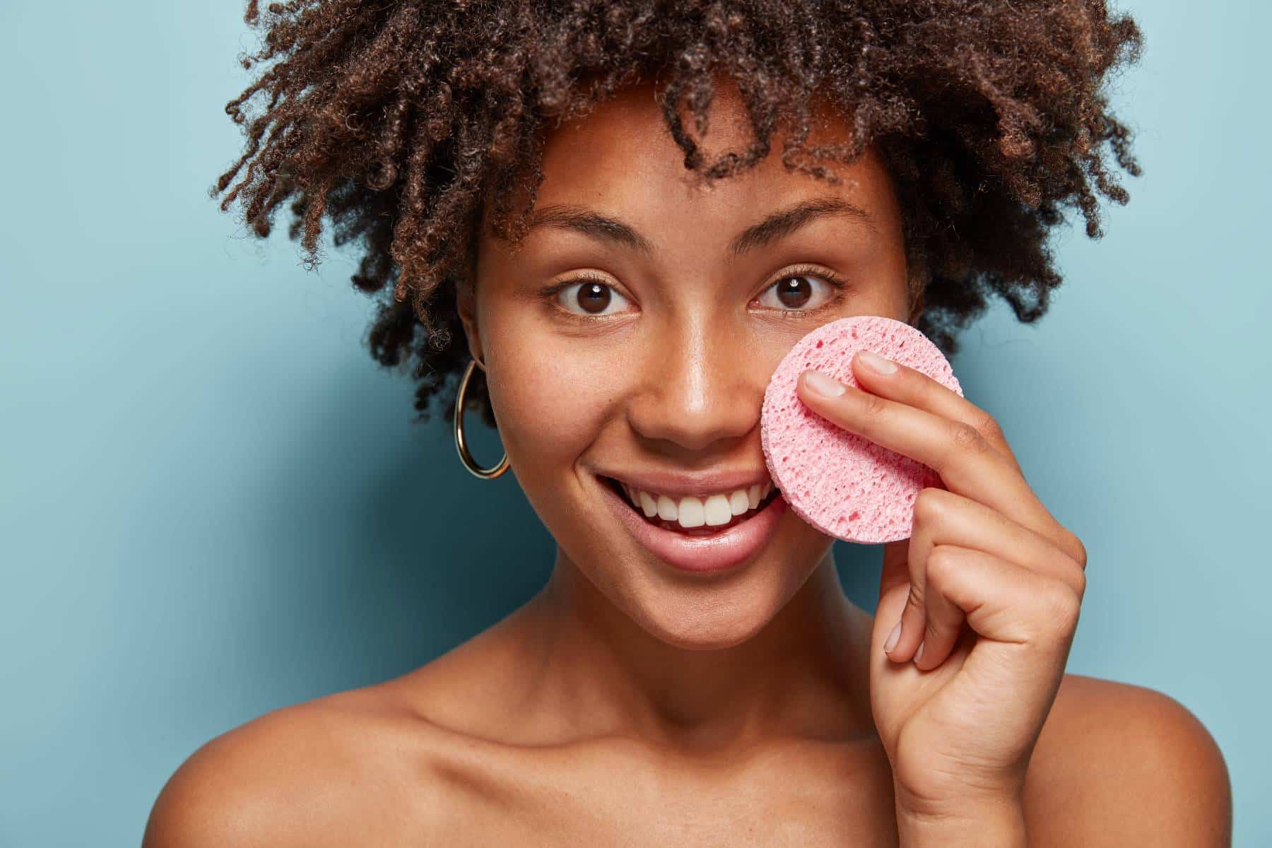 Young African American woman holding exfoliating pad to face